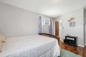 Bedroom with dark wood finished floors and baseboards