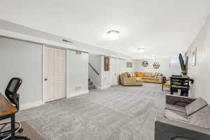 Carpeted living room with stairway and baseboards