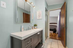 Ensuite bathroom featuring light tile patterned floors, vanity, and a shower stall