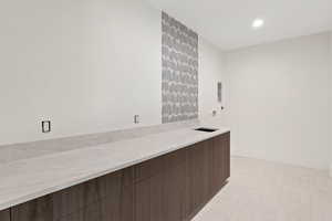 Bar area featuring modern cabinets, dark brown cabinets, recessed lighting, and light stone counters