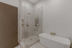 Full bath with a marble finish shower and a soaking tub