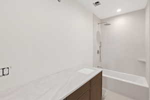 Bathroom featuring tiled shower / bath combo, vanity, light tile patterned floors, and recessed lighting