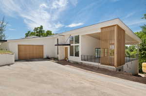 Back of property with driveway, stucco siding, and an attached garage