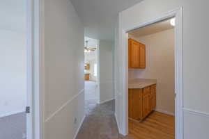 Corridor featuring light wood-type flooring and light colored carpet
