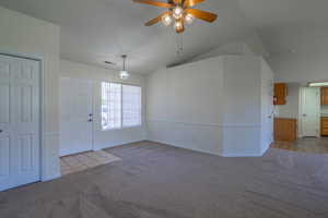 Spare room featuring lofted ceiling, light colored carpet, and a ceiling fan