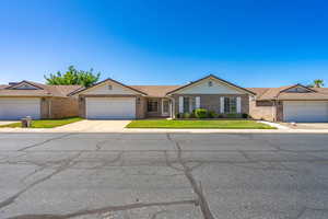 Ranch-style house featuring brick siding, a front yard, driveway, and an attached garage