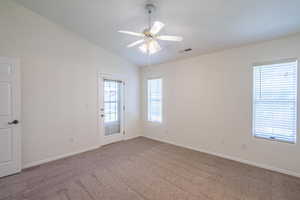 Empty room featuring carpet floors, vaulted ceiling, and ceiling fan