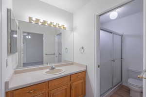 Full bathroom with vanity, a shower stall, ceiling fan, and light wood-style flooring