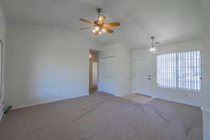 Carpeted empty room with lofted ceiling and ceiling fan