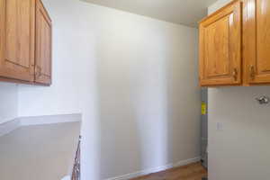 Laundry room featuring cabinet space, light wood-style flooring, and water heater