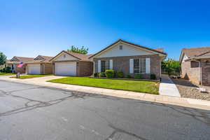View of front of house with a front yard, brick siding, concrete driveway, a garage, and a tiled roof