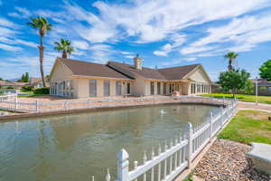 Back of house with a chimney, stucco siding, a water view, and a shingled roof