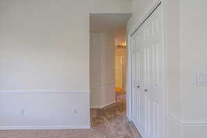 Hall featuring dark colored carpet and baseboards