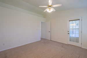 Carpeted empty room with vaulted ceiling and a ceiling fan