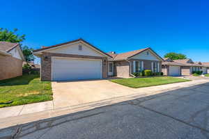 Ranch-style home featuring a front yard, an attached garage, brick siding, and driveway