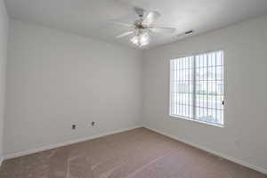 Unfurnished room featuring carpet floors and ceiling fan