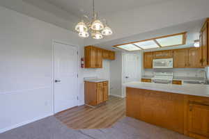 Kitchen with pendant lighting, light countertops, a peninsula, white appliances, and brown cabinetry