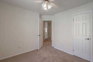 Unfurnished bedroom with light colored carpet and a ceiling fan