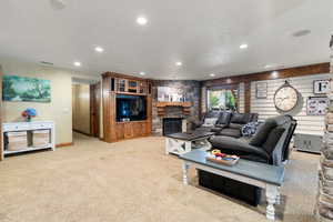Living room featuring light carpet, a stone fireplace, recessed lighting, and a textured ceiling