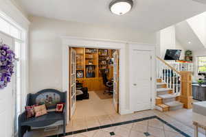 Entrance foyer with inlaid floor details, light tile patterned floors, stairway, and light carpet