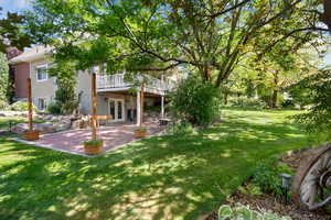 View of green lawn featuring a patio, a deck, and french doors