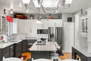Kitchen with glass insert cabinets, light stone countertops, appliances with stainless steel finishes, and a kitchen island