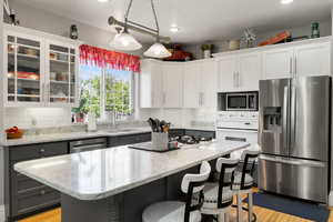 Kitchen featuring stainless steel appliances, tasteful backsplash, hanging light fixtures, light wood-style flooring, and recessed lighting