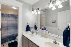 Full bath with double vanity, light tile patterned flooring, and curtained shower