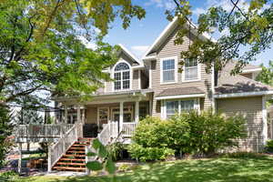 Traditional-style home featuring roof with shingles, covered porch, and stairs