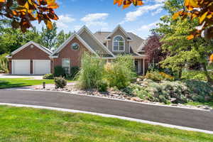 View of front facade with a garage, brick siding, driveway, and a front lawn