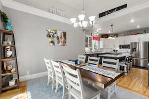 Dining room with light wood-style floors, recessed lighting, crown molding, and a chandelier