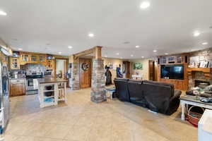 Living room with ornate columns, light tile patterned flooring, recessed lighting, and a fireplace