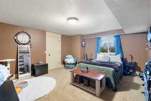 Bedroom with a textured ceiling and light colored carpet