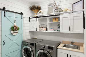 Washroom with cabinet space, washer and clothes dryer, and a barn door