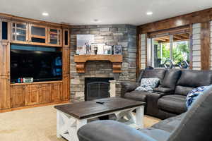 Carpeted living area with a stone fireplace and recessed lighting
