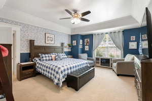 Carpeted bedroom featuring wallpapered walls, crown molding, and a ceiling fan