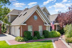 View of front of home with roof with shingles, concrete driveway, a front yard, and brick siding