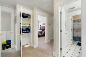 Corridor featuring light colored carpet and light tile patterned floors