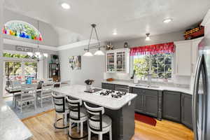 Kitchen with light wood-type flooring, a kitchen bar, plenty of natural light, recessed lighting, and a textured ceiling