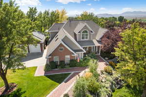 View of front of property featuring a shingled roof, driveway, a front yard, a porch, and an outbuilding