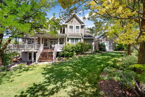 Back of house with stairway, a lawn, a porch, and roof with shingles