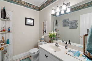 Half bath with light tile patterned floors, vanity, and ornamental molding