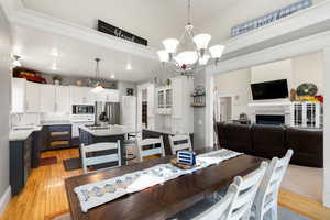 Dining room featuring a fireplace, light wood-type flooring, crown molding, a chandelier, and recessed lighting