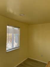 Spare room featuring baseboards and dark wood-type flooring