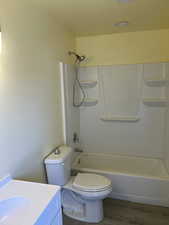 Bathroom with bathing tub / shower combination, vanity, and wood finished floors