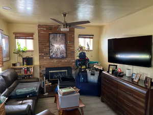 Living area featuring light wood finished floors, a fireplace, and a ceiling fan