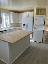 Kitchen with a kitchen island, white cabinetry, white fridge with ice dispenser, light wood-style flooring, and butcher block counters