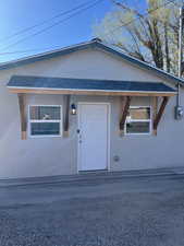 View of front facade featuring stucco siding and roof with shingles