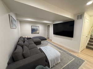 Living room featuring light wood-type flooring, stairs, and recessed lighting