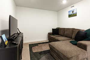 Living area featuring light colored carpet and a textured ceiling